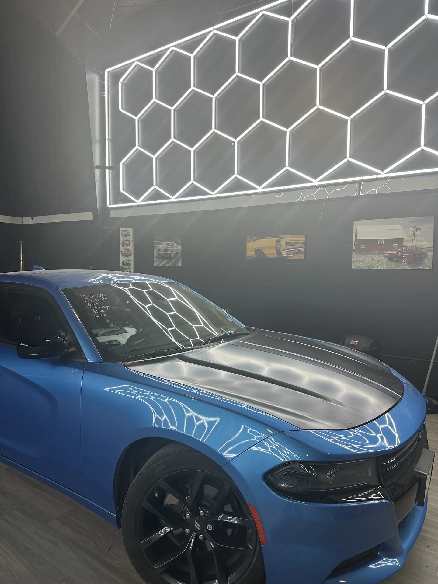 Blue Dodge Charger beneath the shop's dent inspection lights